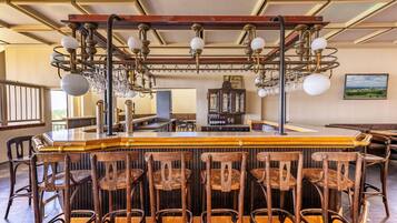 A bar area with wooden chairs, a bar counter, and a chandelier.