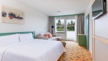 A hotel room with a bed, a sofa, a television, and a window with curtains.