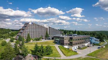 A large hotel with multiple floors, a parking area, and a building with a blue roof.