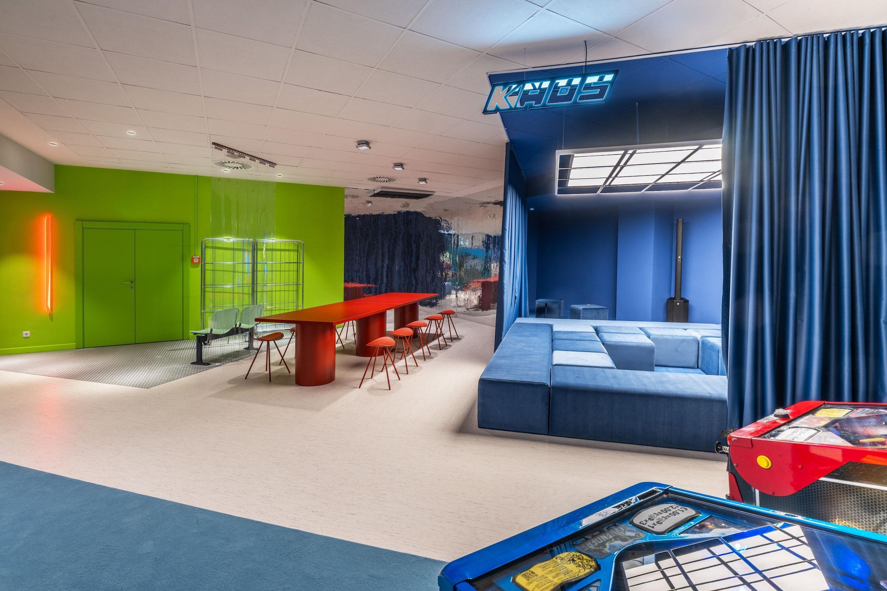 A modern hotel lobby with a green wall, a red table, and a blue seating area.