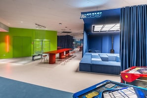 A modern hotel lobby with a green wall, a red table, and a blue seating area. - Appartements im Ferienpark in Schoneck (Schoeneck)
