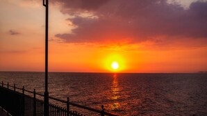 Tramonto sull'oceano con un lampione e una ringhiera.