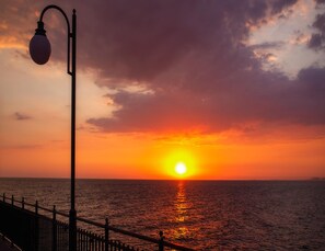 A sunset over the ocean with a street lamp and a railing. - Apartment in Mrzezyno by Sandy Beaches (Trzebiatow)