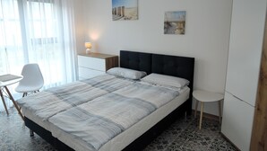 Una camera da letto ordinata con un letto, una scrivania, una sedia e un armadio.