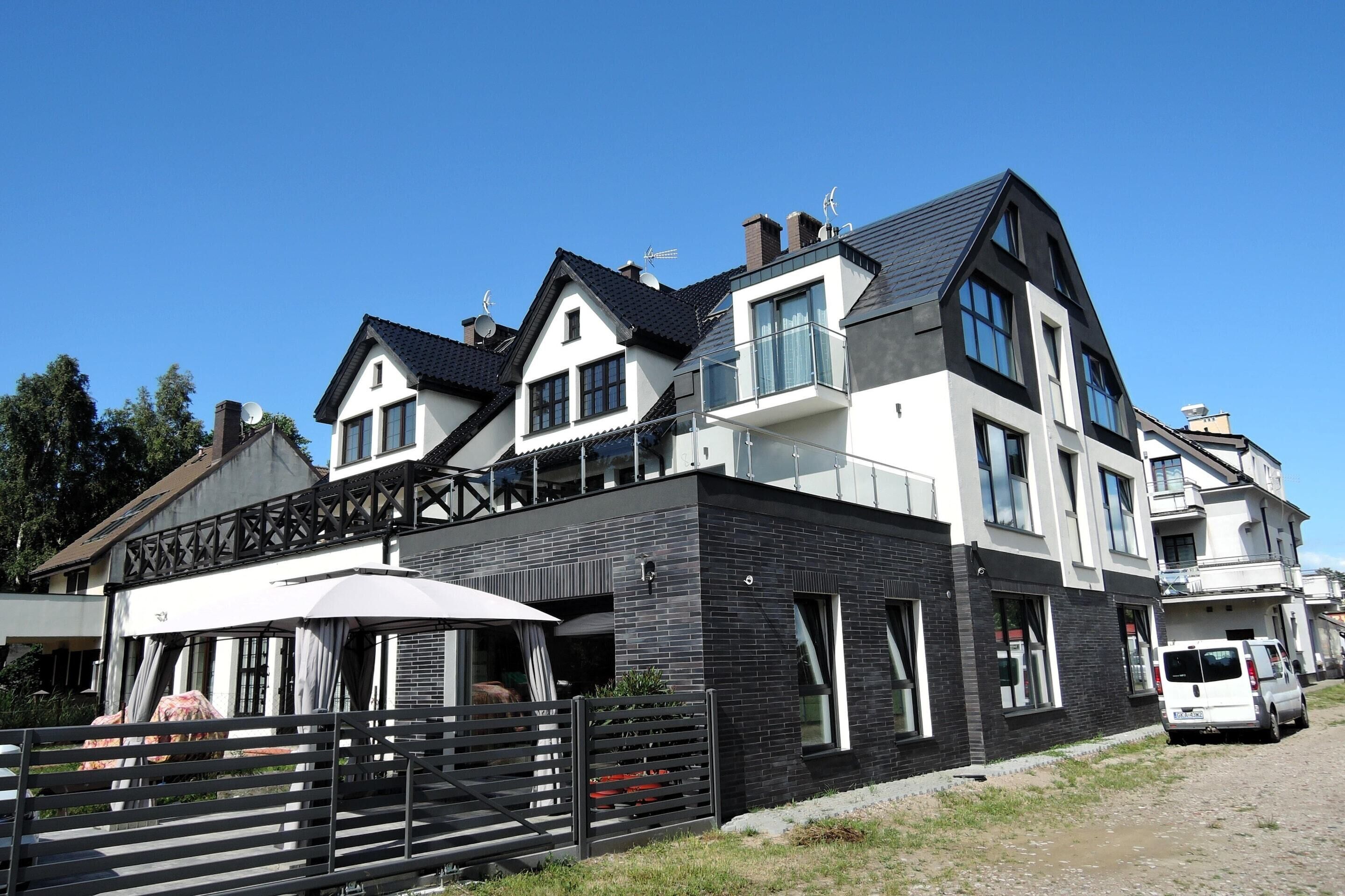 A modern two-story house with a balcony, a garage, and a driveway.