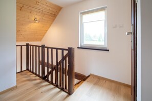 A room with a wooden staircase, a window with a view, and a door. - Brick Cottage Near Baltic Sea and Windmill (gmina Karnice)