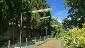A paved path with metal fencing and street lamps, surrounded by greenery and stone walls. - Holiday Home in Citta di Castello With Pool (Città di Castello)
