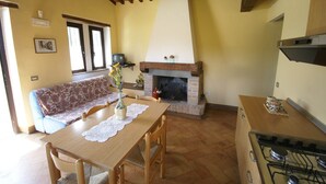 A cozy living room with a fireplace, a dining table, and a sofa. - Holiday Home in Citta di Castello With Pool (Città di Castello)
