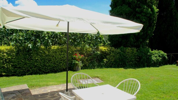 A patio with a white table and chairs, an umbrella, and a stone floor. - Holiday Home in Citta di Castello With Pool (Città di Castello)