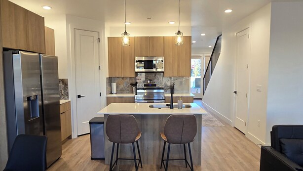 A modern kitchen with stainless steel appliances, wooden cabinets, and a central island with bar stools. - Antelope Canyon Comfy Townhouse - Sleeps 11 (Page)