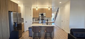 Une cuisine moderne dotée d’appareils électroménagers en acier inoxydable, de meubles en bois et d’un îlot central avec des tabourets de bar.