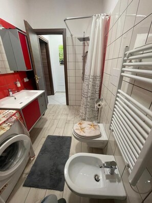 Une petite salle de bain comprenant des toilettes, un bidet, un lavabo et un lave-linge.