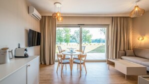 A modern hotel room with a dining area, a sofa, and a TV. - Stranda Residence Apartments Giżycko (Giżycko)