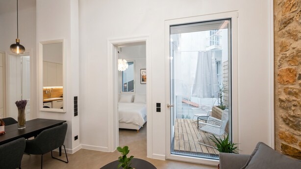 Ein modernes Interieur mit Essbereich, Schlafzimmer und einem Balkon mit Gartenmöbeln.