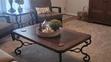 A living room with a ceiling fan, a coffee table with decorative items, a sofa, and a door with a window.