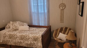 Un dormitorio con cama, una silla, una lámpara y un adorno en la pared.