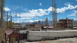 A mountainous landscape with buildings, a bell tower, and a clear sky. - Donskit guest house  (Leh)