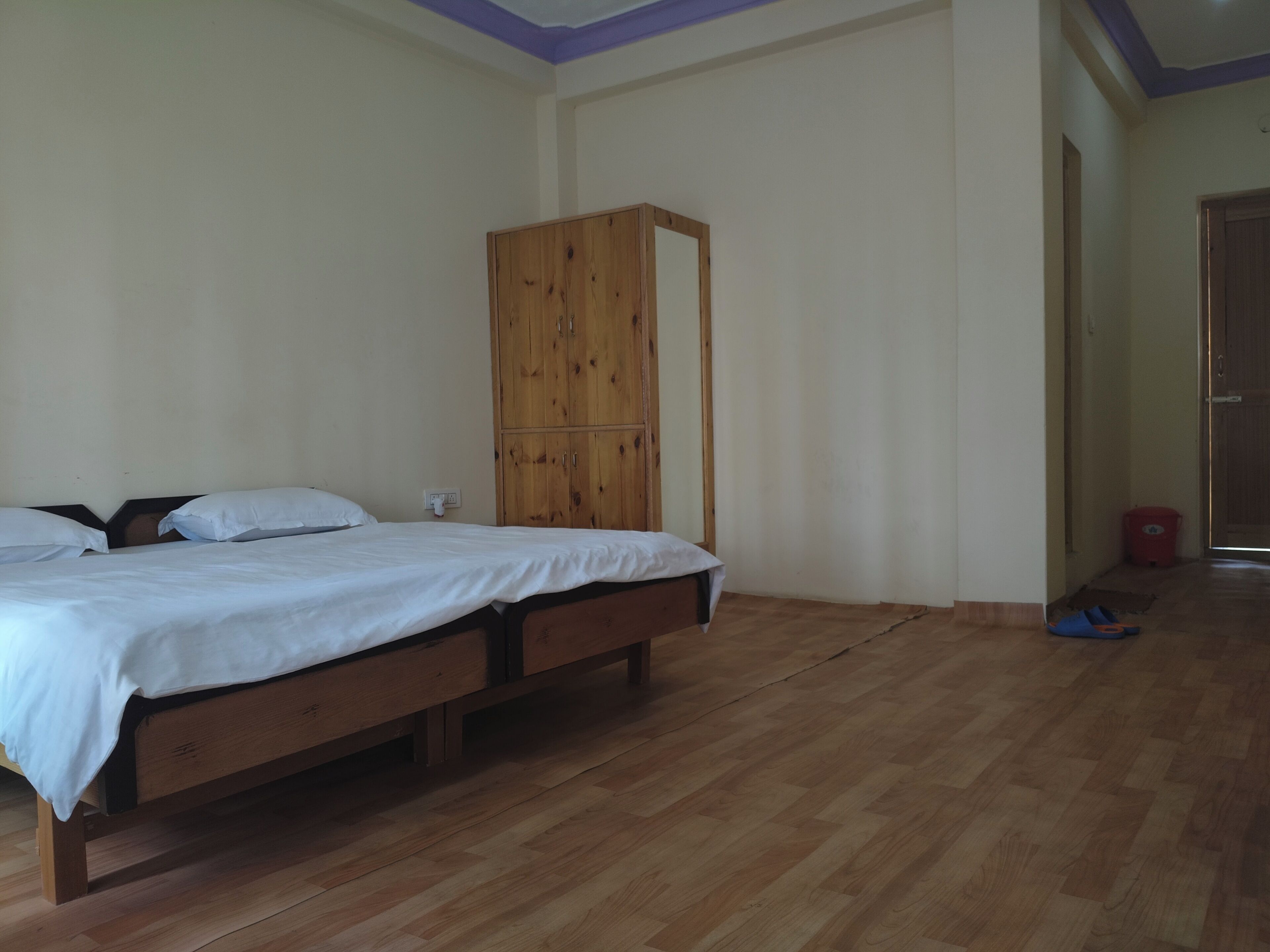 Un dormitorio con cama de madera, un armario y suelo de madera.