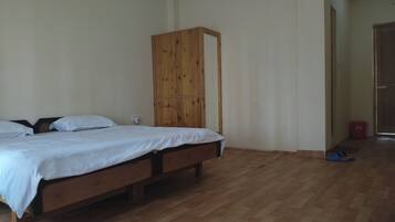 Un dormitorio con cama de madera, un armario y suelo de madera.