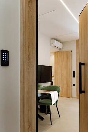 Een moderne kamer met een houten deur, een bureau met stoel, een televisie en een airconditioning.