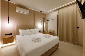 Ein modernes Hotelzimmer mit einem großen Bett, Nachttischen, einem Flachbildfernseher und einer Decken-Klimaanlage.