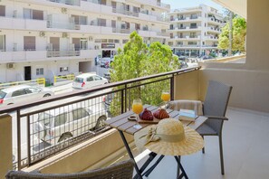 Een balkon met een tafel, stoelen, een hoed en een glas sinaasappelsap.