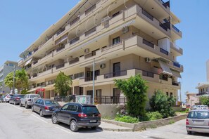 A multi-story residential building with balconies, parked cars, and greenery. - Lyvoa Modern Living by the sea (Rethymno)