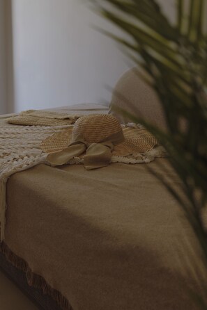 Een bed met een beige deken en een gevlochten mand.
