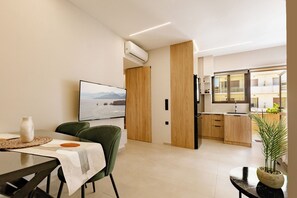 A modern kitchen with wooden cabinets, a dining area with a table and chairs, and a view of the sea through a large window. - Lyvoa Modern Living by the sea (Rethymno)