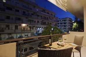 A balcony with a table set for dining, a bottle of wine, and a glass of wine. - Lyvoa Modern Living by the sea (Rethymno)
