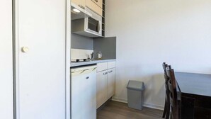 Eine kleine Küche mit einer Mikrowelle, einem kleinen Mülleimer und einem Esstisch mit Stühlen.