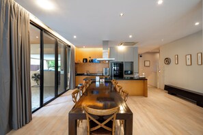 A modern kitchen with a dining area, large windows, and a sliding glass door.