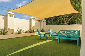 Eine Terrasse mit künstlichem Rasen, zwei Stühlen, einem Tisch und einer Bank.