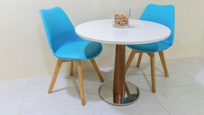 A round white table with two blue chairs, a glass container with items, and a wooden floor. - IslaRita Stays - spacious studio near Eagle Beach (Oranjestad)
