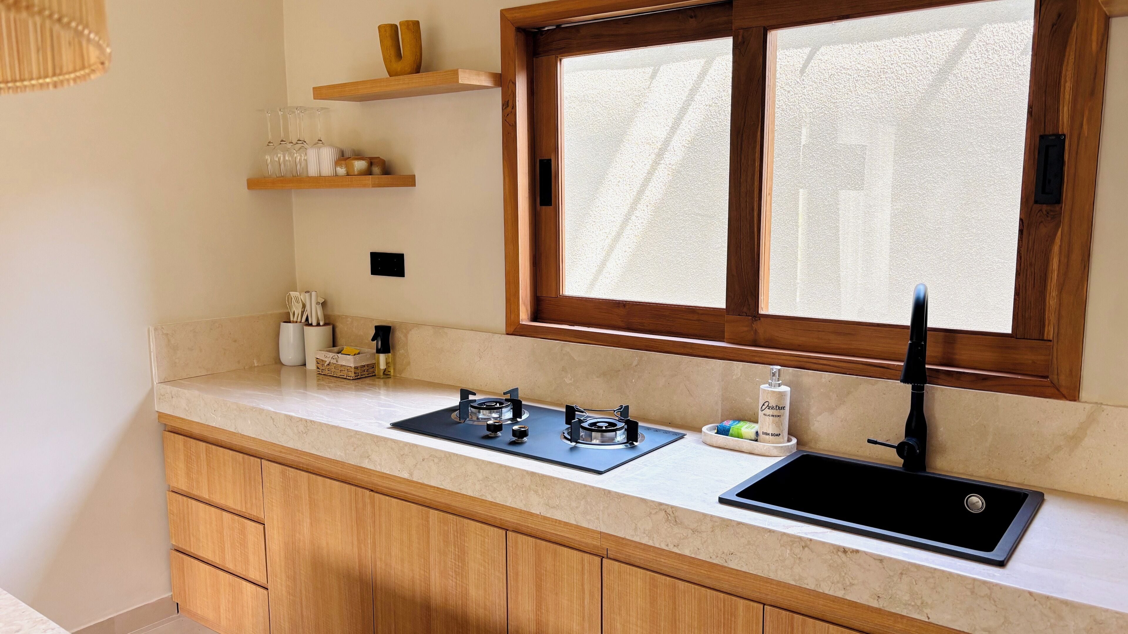 A kitchen with a window, wooden cabinets, a sink, and a countertop with various items.