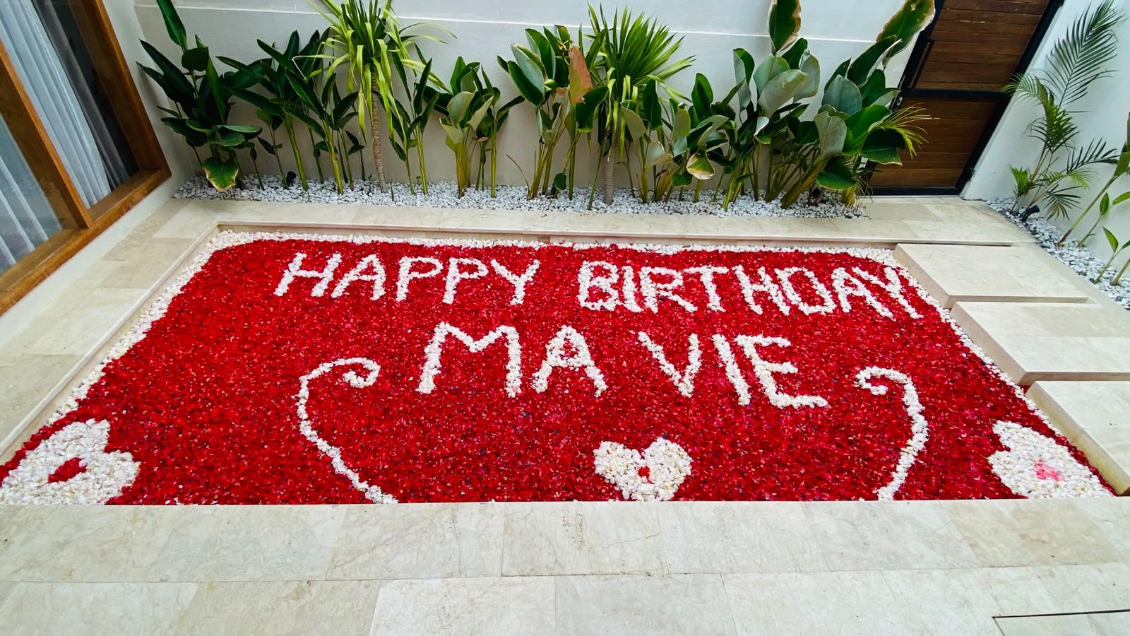 Una alfombra roja y blanca con estampado floral que dice 'HAPPY BIRTHDAY MAVI'.