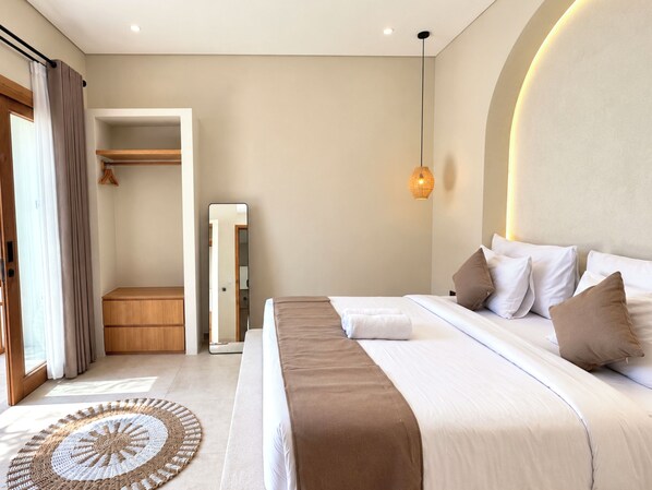Une chambre d’hôtel avec un grand lit, une table de chevet, une armoire et un miroir.