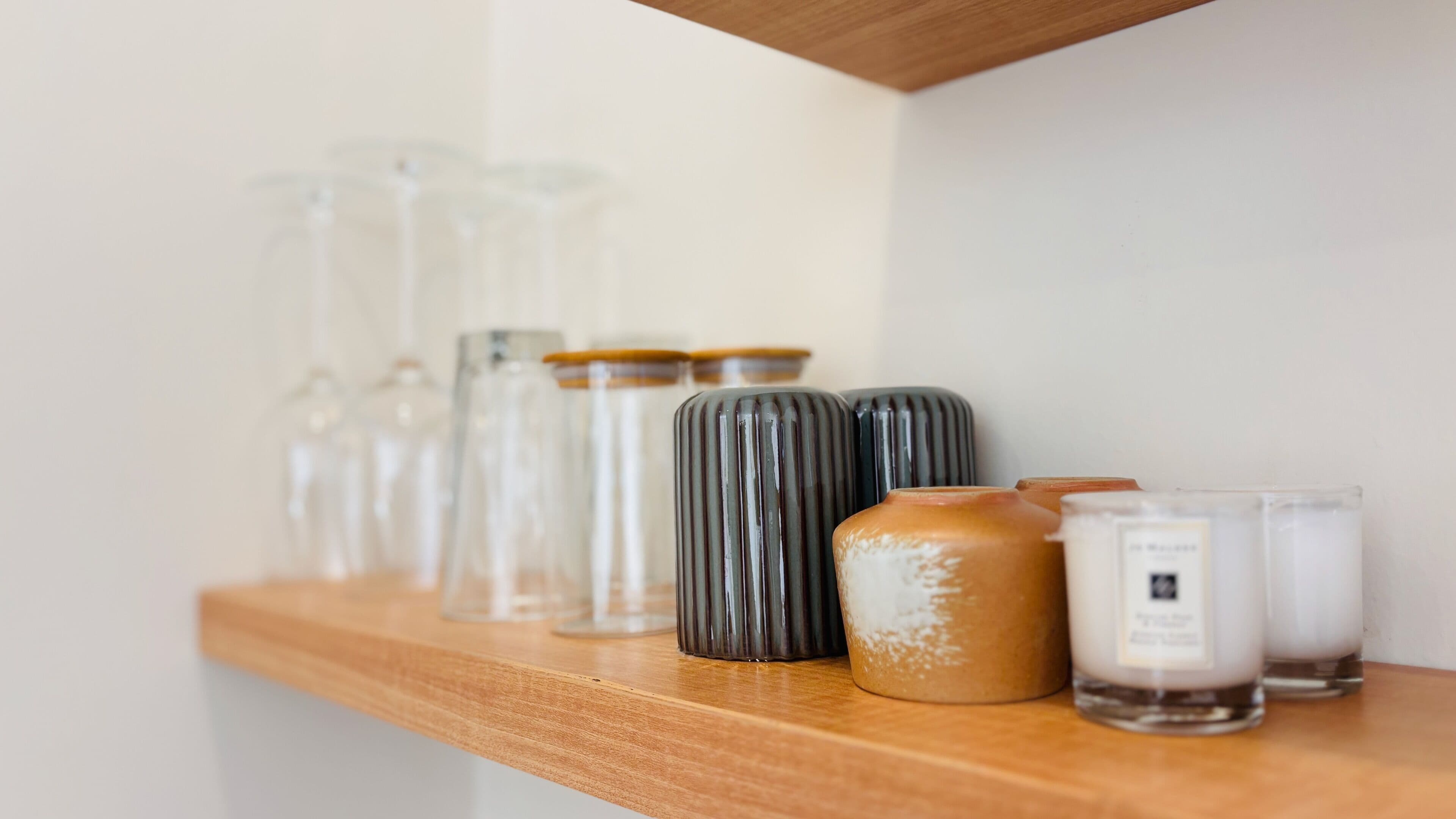 A wooden shelf with various glass containers and jars.