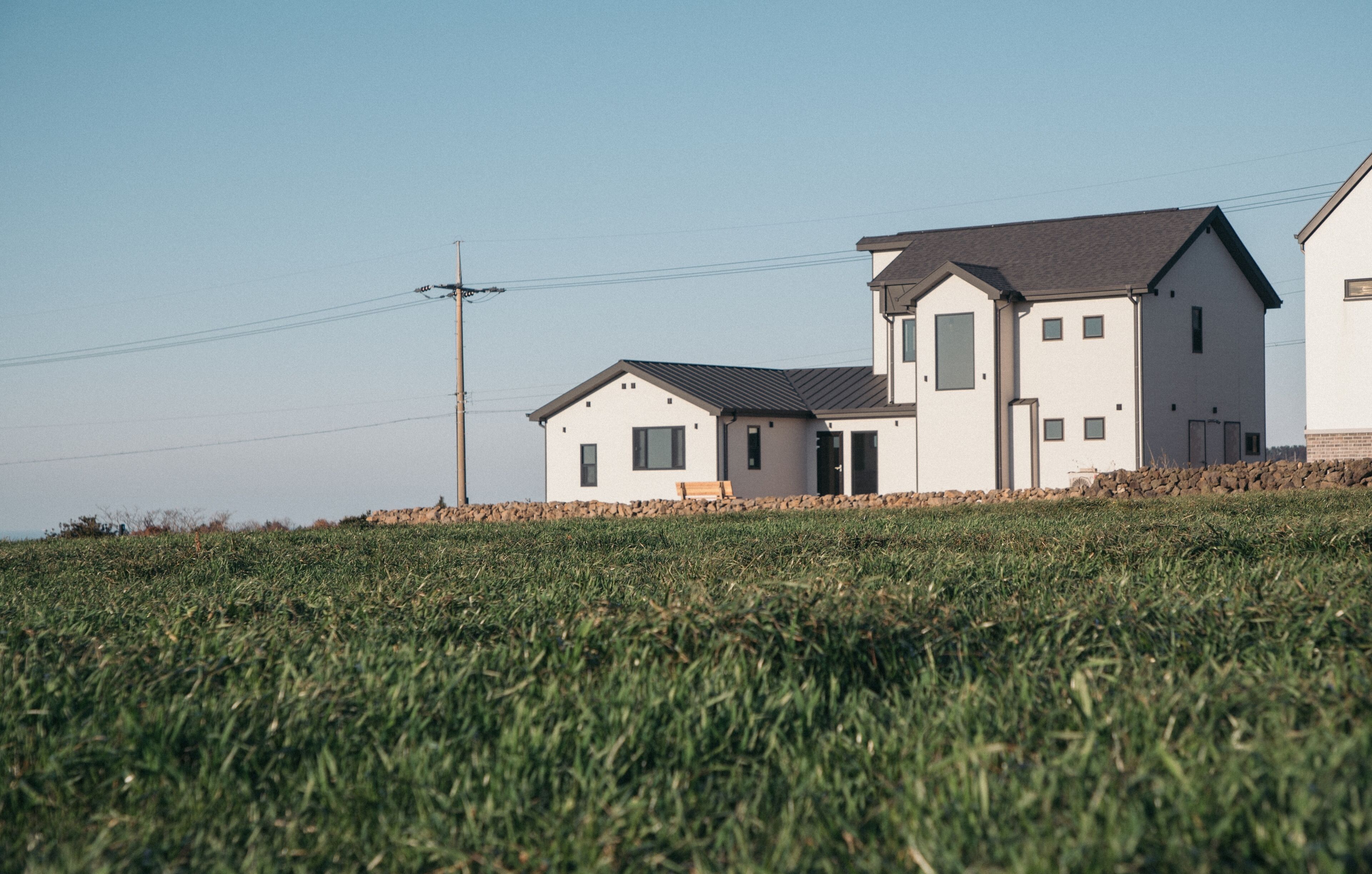 A modern two-story house with a flat roof, a small porch, and a stone foundation.