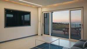 A modern room with a large sliding glass door leading to an outdoor patio, a small table, and a sofa.