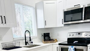Una cucina moderna con pensili bianchi, un forno in acciaio inossidabile, un microonde e una macchina da caffè.