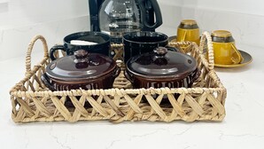 Una cucina con una macchina da caffè, barattoli e un cesto in vimini sul piano di lavoro.