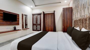 A hotel room with a bed, a flat-screen TV mounted on the wall, a wooden wardrobe, and a stone-patterned wall.