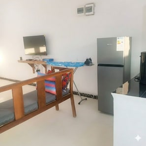 Une cuisine de taille réduite, équipée d’un réfrigérateur, d’une petite table et d’une chaise.