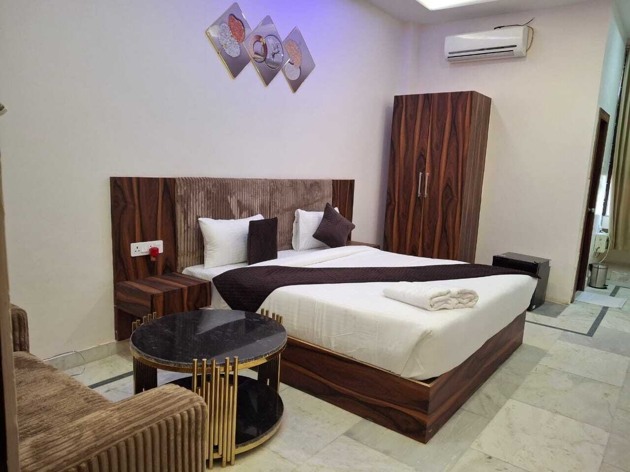 Una habitación de hotel con una cama grande, una mesa redonda, un armario y un aire acondicionado instalado en la pared.