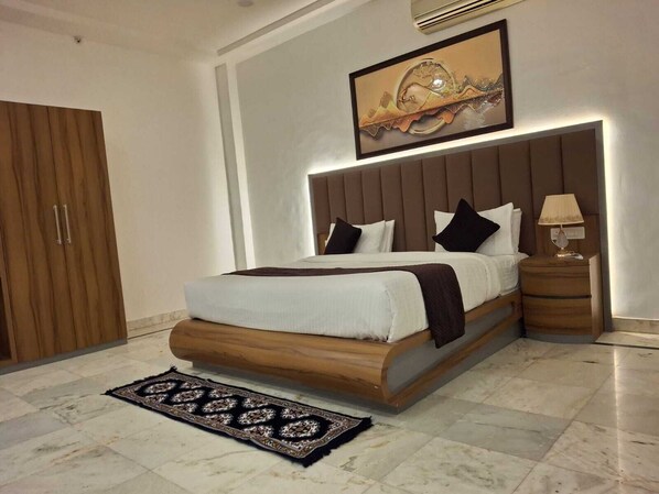 A modern bedroom with a large bed, a nightstand, a wooden wardrobe, and a wall-mounted artwork. - Gonard By Melting Moments (Gonda)