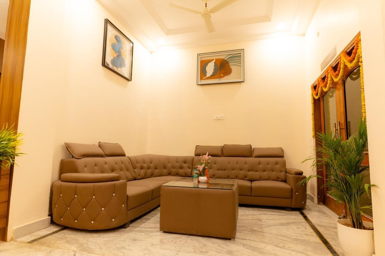 Sala de estar con sofá seccional, una mesa de centro de vidrio y dos cuadros colgados en la pared.
