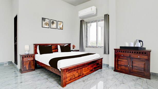 A bedroom with a wooden bed, a nightstand, a dresser, an air conditioner, and a window with curtains. - Deluxe Hotel Lara Heritage (Amer)