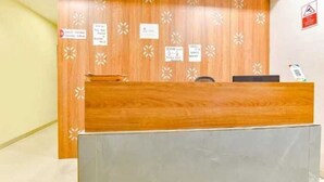Ένας πάγκος υποδοχής με έναν τοίχο επενδυμένο με ξύλινα πάνελ, έναν γκρι πάγκο και αρκετές ενημερωτικές πινακίδες.