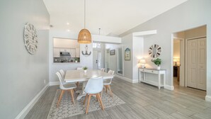 A modern dining area with a white table, chairs, and a hanging light fixture. - Huge Pool, Near Beaches, IMG, UTC, Great Clubhouse (Bradenton)